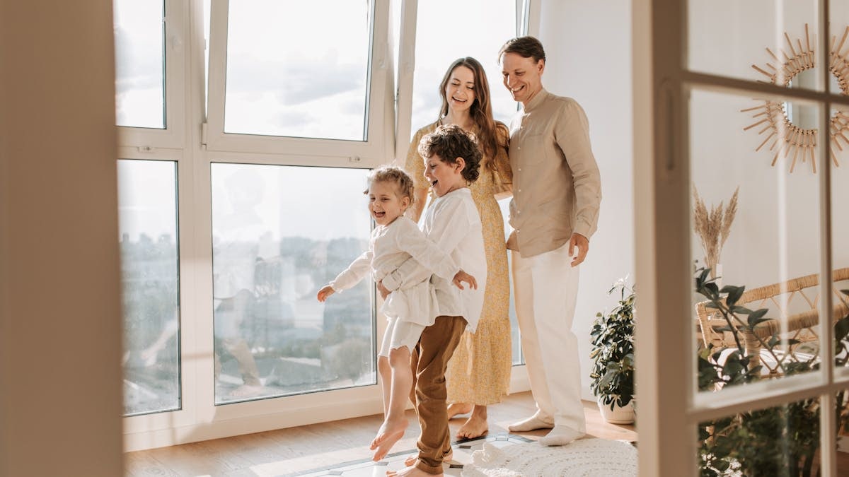 A joyful family of four enjoying time together in a bright, modern living room.